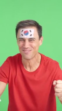 Stüdyoda, Güney Kore 'ye coşkuyla tezahürat eden ve ulusal bayrak sallayan bir adamın krom görüntüsü var.