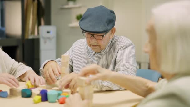 介護施設で木製のスキルボードゲームで遊ぶ3人のシニアの後期旅行のビデオ — ストック動画