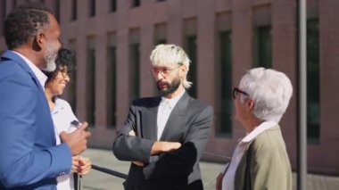 Finansal bölgede rahatça konuşan bir grup çok ırklı iş adamının videosu.