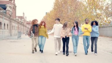 Şehirde sohbet eden ve rahatça yürüyen bir grup gencin yavaş çekim videosu.