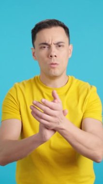 Stüdyoda mavi arka planı olan bir adam kameraya bakıp gittikçe daha hızlı alkışlıyor.