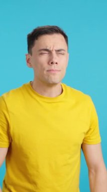 Stüdyoda mavi arka planda kafasını sallayan ve kameraya bakan bir adamın videosu var.