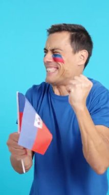 Stüdyoda Haiti için tezahürat yapan tutkulu ve gergin bir adamın krom görüntüsü var.