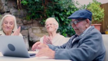 Yaşlı bir adamın laptopla yaptığı video görüşmesi sırasında alkışladığı üç kişinin videosu.