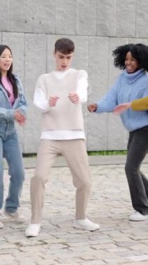 Şehirde dans eden çok ırklı mutlu genç bir grubun yavaş çekim videosu.