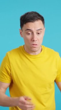 Stüdyoda, nefesi kokan bir adamın mavi arka planlı videosu var.