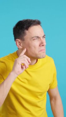 Stüdyoda, kendisine defalarca söylenenleri iyi dinlemeyen bir adamın mavi arkaplanlı videosu var.