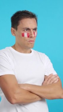 Stüdyoda, yüzünde Peru bayrağı olan bir adamın ciddi bir ifadeyle bakışlarını çevirdiği bir video.