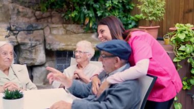 Yaşlılar ve hemşirelerin yaşlılar bahçesinde konuşup güldüğü videolar.