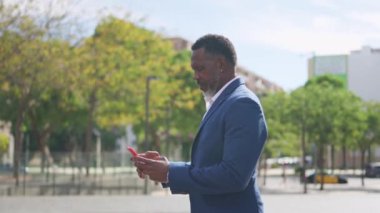 Yetişkin bir Afrikalı iş adamının açık havada telefonla mesaj gönderdiğini gösteren bir video.