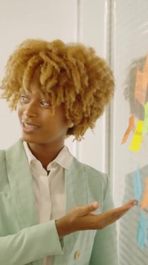 Afrikalı bir kadının bir toplantıda fikir beyan etmesi için bir post-it göstermesinin yavaş çekim videosu.