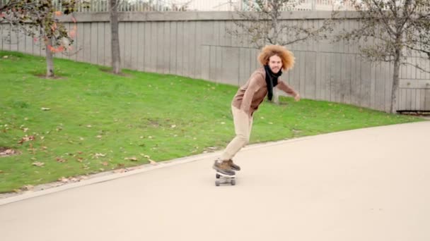 在一个城市公园里一个留着卷发滑板的年轻人的慢镜头 — 图库视频影像