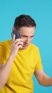 Stüdyoda cep telefonuyla konuşan bir adamın mavi arkaplanlı videosu. Çerçeve boş başlar, adam aşağıdan görünür ve altta kaybolur..