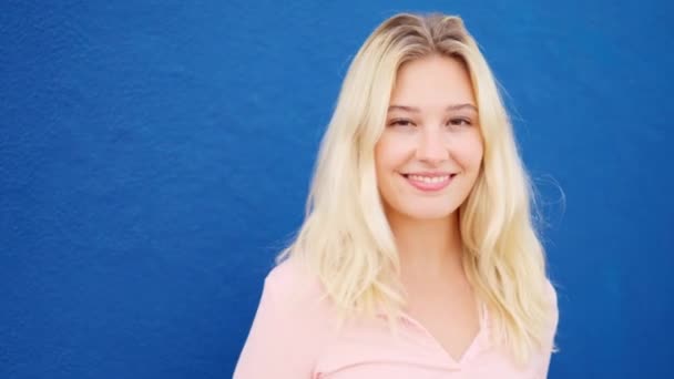 Vidéo Ralenti Une Femme Blonde Souriant Caméra Côté Mur Bleu — Video