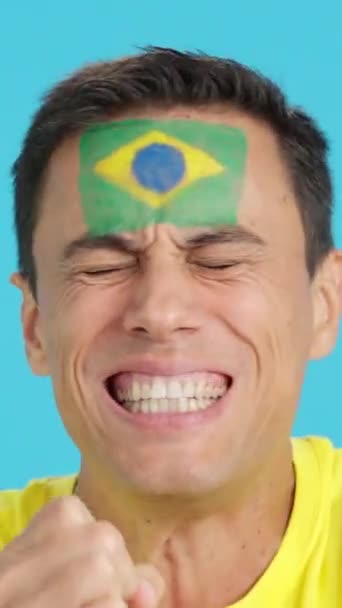 在演播室里用彩色的特写拍摄了一个非常紧张的男人 脸上挂着巴西国旗 在一场比赛中支持巴西队 这场比赛最后以失败告终 — 图库视频影像