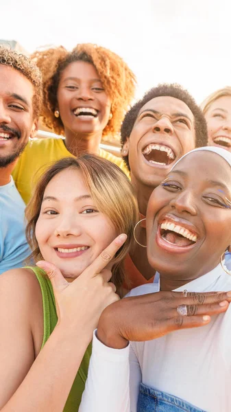 Group of excited multiethnic friends taking selfie outdoors during sunset
