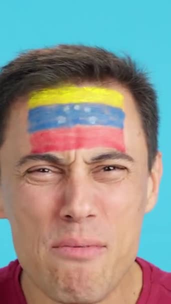 ベネズエラのチームをサポートする顔にベネズエラの旗を塗られた男のクロマのスタジオでのビデオ — ストック動画