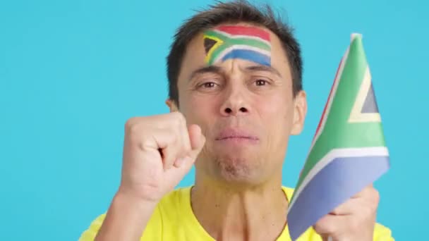 在演播室里用彩色的近距离录像拍摄一个脸上挂着南非国旗的非常紧张的男人 他在一场最后以失败告终的艰难比赛中支持着南非队 — 图库视频影像