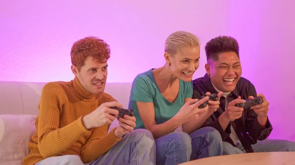 Group of excited multiethnic friends playing console at home