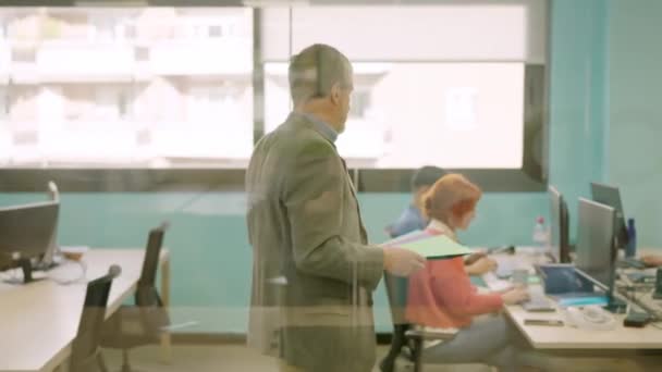 コワーキングスペースの従業員にファイルを配信する成熟した男性の横のスローモーションビデオ — ストック動画