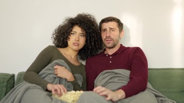 自宅でポップコーンを食べるテロ映画を見ている多民族カップルのスローモーションビデオ — ストック動画