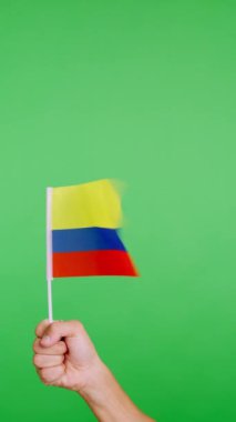 Stüdyoda yavaş çekim videosu, rüzgarla sallanırken Kolombiya flamasını kaldıran bir elin kromasıyla.