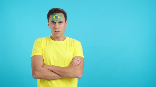 摄影棚里的录像 彩色的是一个有尊严而严肃的男人 脸上挂着巴西国旗 带着尊严地看着摄像机 — 图库视频影像