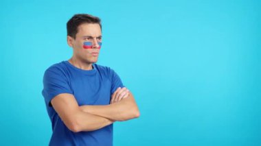 Stüdyoda, yüzünde Haiti bayrağı olan bir adamın ciddi bir ifadeyle yüzünü boyadığı bir video.