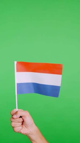 風で振りながらオランダのペナントを持ち上げる手のクロマとスタジオでのスローモーションビデオ — ストック動画