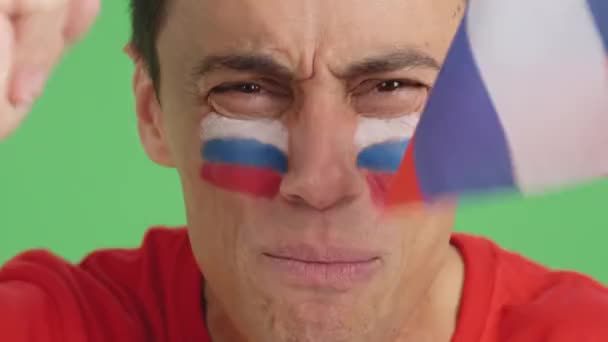 ロシアのチームをサポートする顔にロシアの旗を塗った男のクロマのスタジオでのビデオ — ストック動画