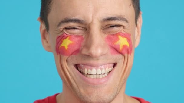 摄影棚里的录像 彩色的是一个男人的特写 他脸上挂着越南国旗 在镜头前微笑 — 图库视频影像