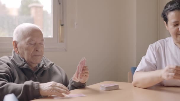 一些老年人和照顾者在疗养院一起打牌的慢镜头 — 图库视频影像