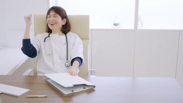 女性医師のスローモーションビデオ 何かを祝い 彼女のオフィスで救済とサイン — ストック動画