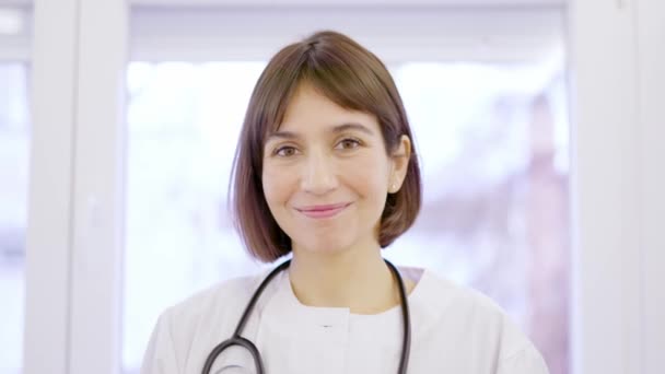 一名身穿实验室外套的女医生对着诊所的摄像机微笑的慢镜头 — 图库视频影像