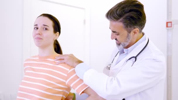 クリニックの女性の痛みを調べる成熟した医師のスローモーションビデオ — ストック動画