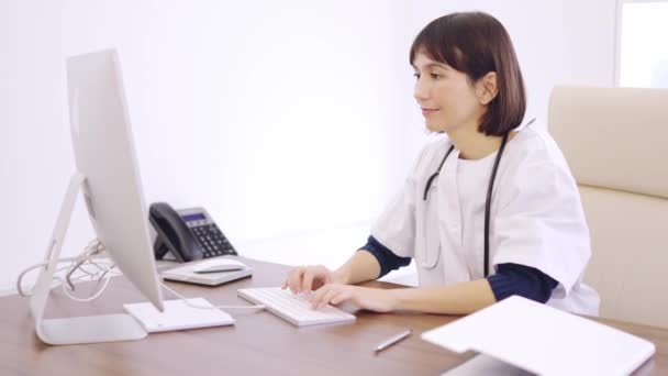 一名女医生在诊所用电脑慢镜头 对着摄像机微笑的慢镜头 — 图库视频影像