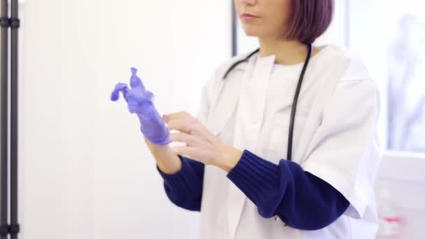 一名无法辨认的女医生在诊所戴上乳胶蓝色手套的慢镜头 — 图库视频影像