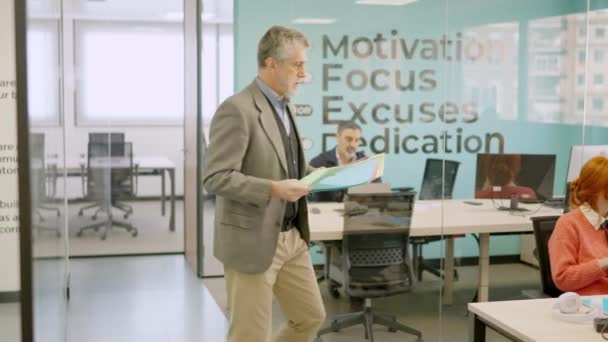 성숙한 보스의 슬로우 비디오는 사무실에서 직원들에게 폴더를 제공합니다 — 비디오