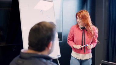 Yatay ağır çekim videosunda bir kadın, bir toplantı odasında sunum sırasında bir fikri açıklarken görülüyor.