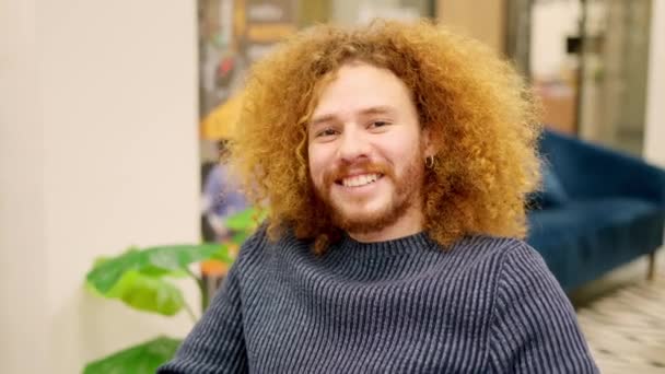 一个卷曲头发的男人穿着工作服对着相机微笑的水平慢镜头 — 图库视频影像