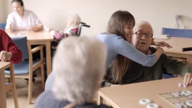 Yaşlı büyükbabasını kucaklayan ve öpen mutlu bir torunun yavaş çekim videosu.