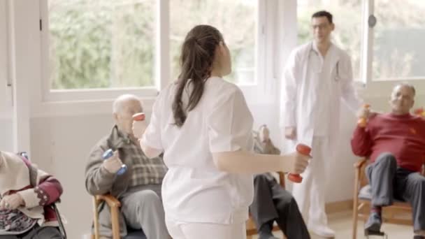 一位女性理疗师在疗养院向一群长者讲解运动的慢镜头 — 图库视频影像