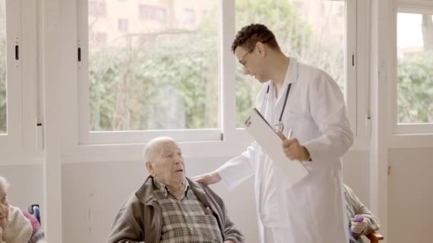 一名男医生站在养老院里与一名老年人进行例行医疗检查的慢镜头 — 图库视频影像