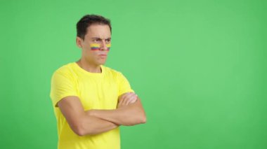 Stüdyoda, yüzünde Kolombiya bayrağı olan bir adamın ciddi bir ifadeyle yüzünü boyadığı bir video.
