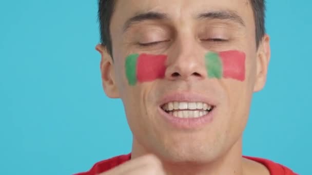 在演播室里用彩色照片近距离拍摄一个脸上挂着葡萄牙国旗的非常紧张的男人 在最后的一场比赛中 他支持着葡萄牙球队 但这场比赛最终以失败告终 — 图库视频影像