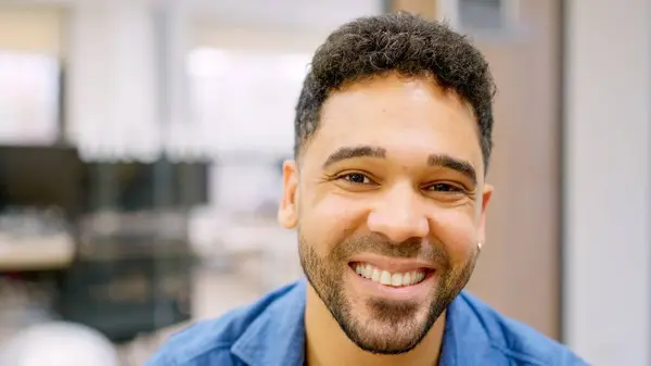 Happy hispanic man smiling at camera working in a coworking