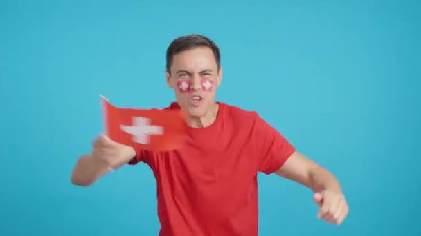 在演播室里播放了一个男人为瑞士呐喊和挥动国旗而热烈欢呼的画面 — 图库视频影像
