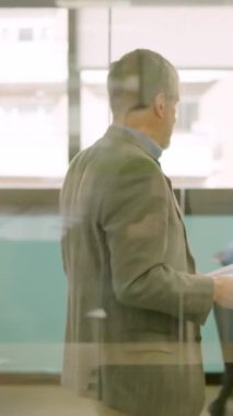 Yetişkin bir adamın çalışma alanındaki çalışanlara dosya teslimatı yaptığı yavaş çekim videosu.