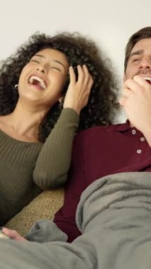 Çok ırklı bir çiftin evde eğlenceli filmler izlerken gülüşlerinin yavaş çekim videosu.