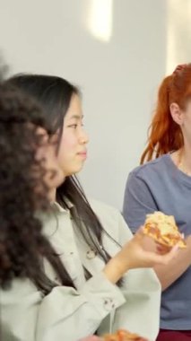 Çok ırklı bir arkadaşın evde oturup pizza yerken gülümsediği yavaş çekim videoları.